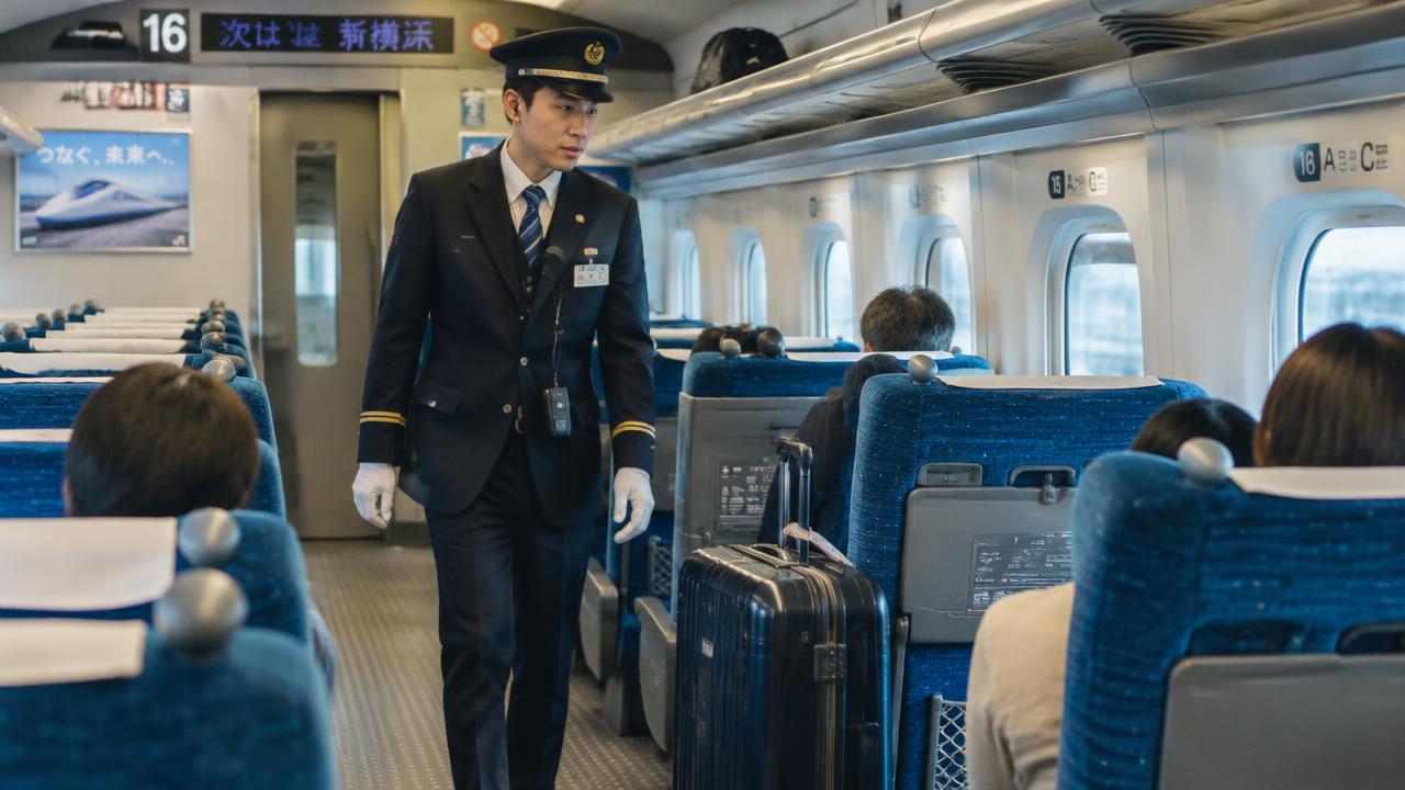Shinkansen conductor walking past a large suitcase