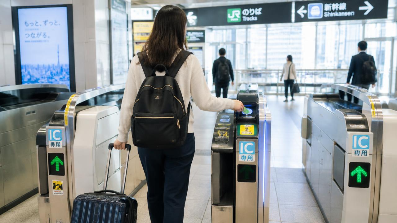 Traveller tapping an IC card at a subway gate with a suitcase